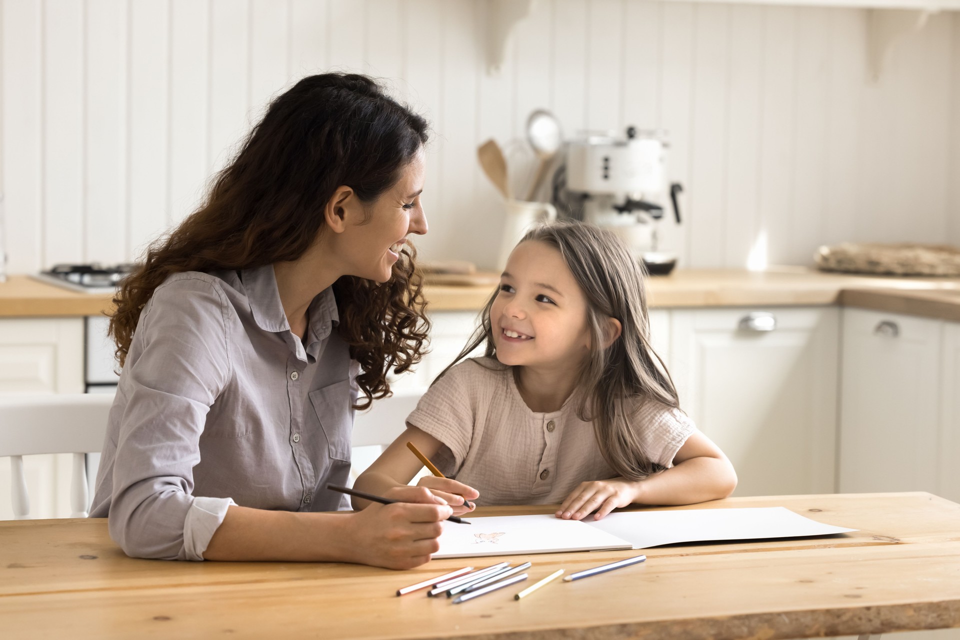 Nanny and daughter drawing with colored pencils at home
