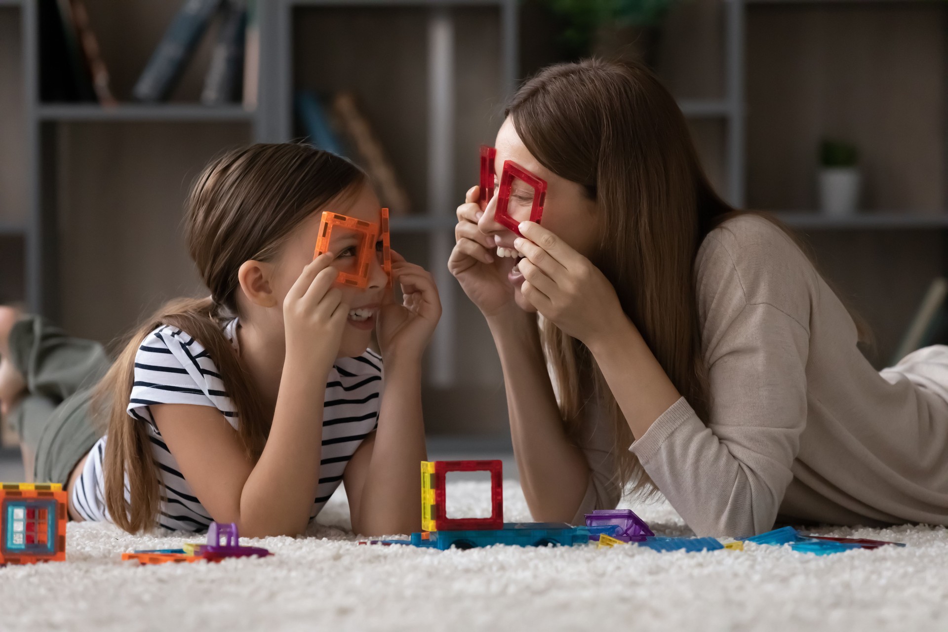Smiling mom and little daughter play together